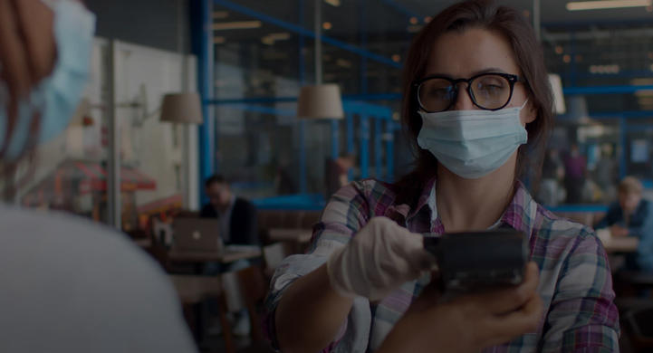 woman wearing a mask purchases food using contactless payments