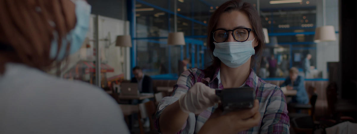 woman wearing a mask purchases food using contactless payments