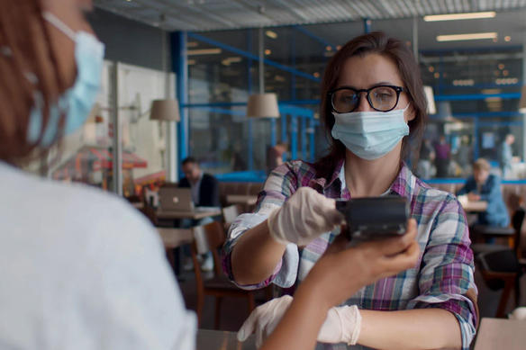 woman wearing a mask purchases food using contactless payments