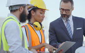 a female warehouse working speaking to a male coworker and a man in a suit