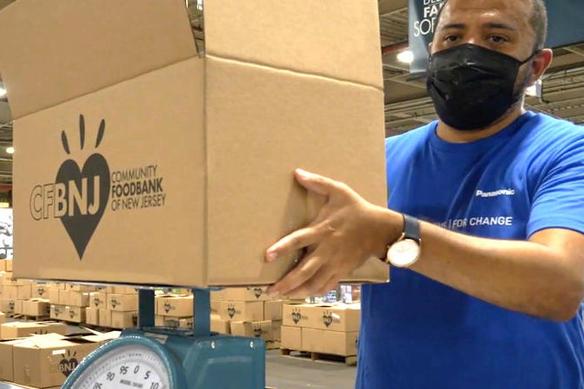 A Panasonic employee volunteer helps carry boxes at the Community Food Bank of New Jersey