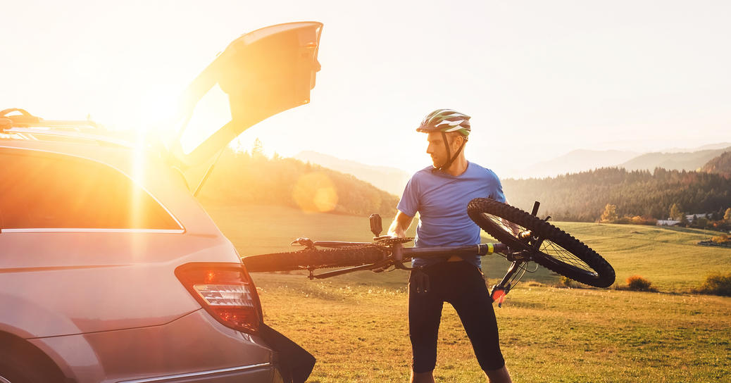 A cyclist putting his bicycle in the trunk using hands-free voice commands to open the trunk