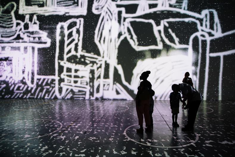 a family stands silhouetted by the projections of the van gogh exhibit